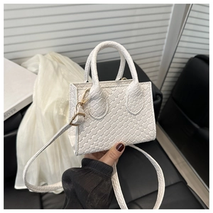 Close-up of a white woven handbag featuring gold hardware and a detachable shoulder strap