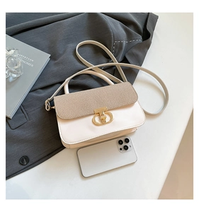 Detail of compact two-tone leather handbag with woven flap and gold metal clasp