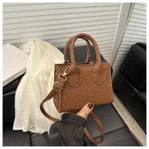 Detail of brown woven leather texture on a mini tote bag with gold metal hardware