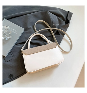 Detail of cream white leather handbag featuring woven texture flap and gold hardware