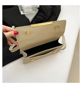 Detail of beige woven texture crossbody bag with gold magnetic buckle and black interior