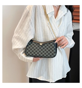 Detail of vintage black shoulder bag with M jacquard pattern and gold metal logo