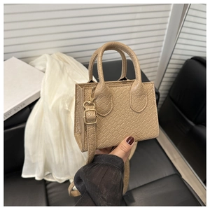 Detail of beige crocodile pattern mini handbag with gold hardware and removable strap