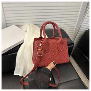 Detailed close-up of the red woven leather mini tote featuring gold-tone metal hardware
