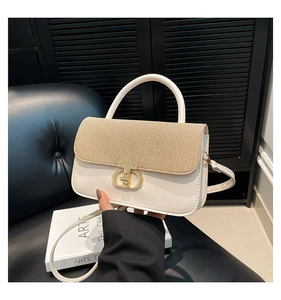 Detail of elegant top-handle handbag with woven texture flap and golden buckle on leather seat