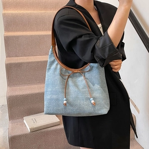 Hellblaue Schultertasche mit Schleife und braunen Lederriemen am Modell präsentiert