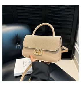 Close-up of beige woven texture flap and golden metal clasp on a luxury handbag