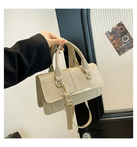Close-up of champagne gold crossbody bag with luxury woven texture and metal bar detail