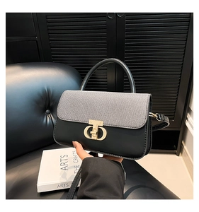Detail view of two-tone luxury handbag with gold interlocking logo buckle on leather chair