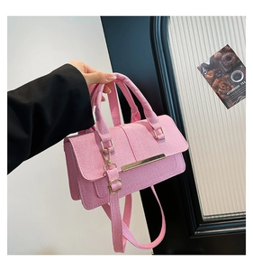 Close-up of pink textured handbag with gold metal trim and cylindrical handle detail