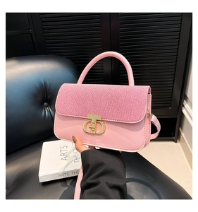 Detail of light pink crossbody bag with textured flap and gold metal twist-lock clasp