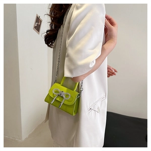 Dettaglio mini borsa quadrata verde lime con fiocco di strass lucidi e catena argento