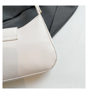 Detail of cream white half-moon bag with gold hardware and fine stitching texture