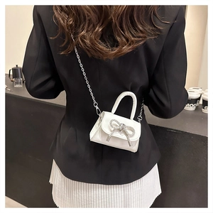 Dettaglio mini borsa bianca con fiocco di strass e tracolla a catena argento