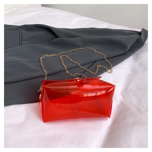 Dettaglio borsa trasparente in PVC rosso con catena dorata su un blazer grigio