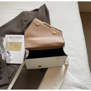 Detail view of cream structured handbag featuring gold magnetic buckle and brown lining