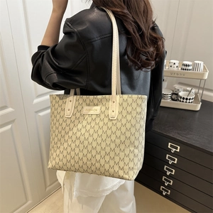 Minimalist cream tote bag with M-letter print and fashion plaque shown on model shoulder