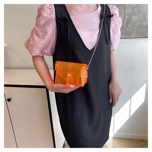 Détail du mini sac bandoulière tendance en PVC orange avec une fine bandoulière en chaîne