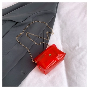 Dettaglio della mini borsa in PVC rosso trasparente con catena dorata e bottone