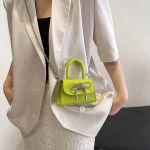 Mini borsa verde lime con fiocco di strass e catena dorata mostrata su modella