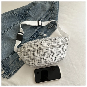 Détail du sac banane en tweed à carreaux sur tissu blanc avec veste en jean