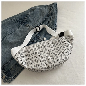 Détail d'un sac de poitrine à carreaux noir et blanc avec sangle blanche sur veste en jean