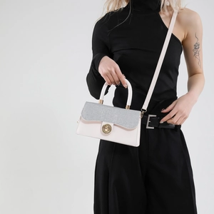 Pink crossbody bag with glitter flap and gold lock shown on model with black outfit