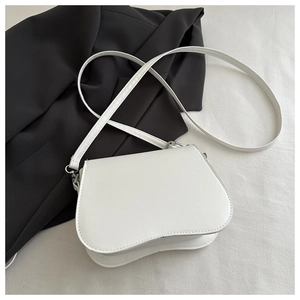 Close-up of cream crossbody bag featuring a unique wavy base design and silver hardware
