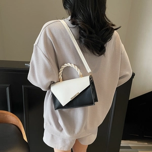 Minimalist black and white contrast handbag with woven handle and adjustable strap