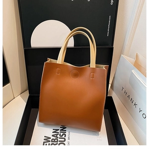 Detail of vintage brown leather tote bag with cream handles in premium gift packaging