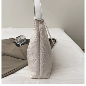 Detailed close-up of the white woven texture and leather craftsmanship of a large tote bag
