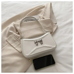 Détail du sac en cuir blanc avec nœud argenté et textures géométriques élégantes