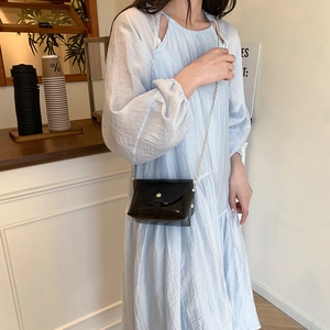 Mini borsa a tracolla nera chic con catena dorata in un ambiente caffè elegante