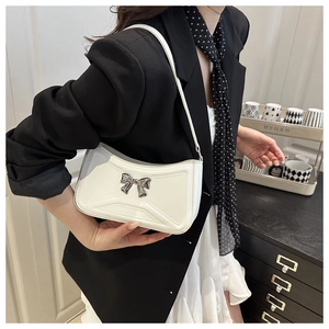 Détail du sac croissant en similicuir blanc avec un nœud en métal argenté élégant