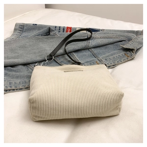 Detail of beige corduroy tote bag showing textured fabric and silver metal ring strap attachment