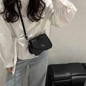 Minimalist black asymmetrical saddle crossbody bag with Fashion Trend white typography