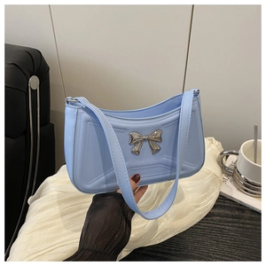 Gros plan sur sac sous le bras bleu clair avec nœud argenté et texture géométrique