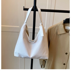 Close-up of white woven texture bucket bag with wide strap and fashion hangtag