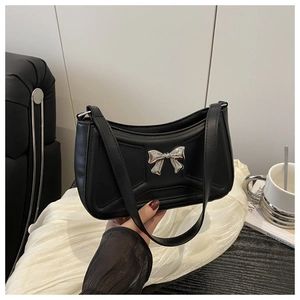 Gros plan d'un sac à bandoulière en cuir noir mat avec boucle nœud en métal argenté chic