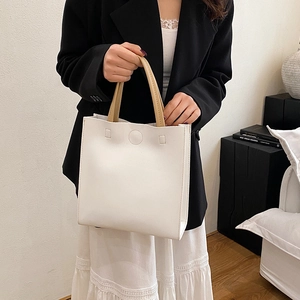 Minimalist white leather tote bag with camel handles and circular embossed detail