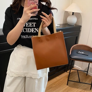 Minimalist brown square tote bag with beige top handles shown in a daily lifestyle setting