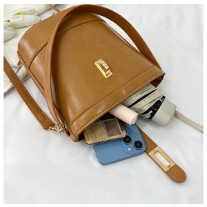 Interior storage detail of the brown bucket bag showing umbrella, phone and cosmetics