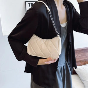 Quilted beige underarm bag with silver chain strap shown worn over the shoulder