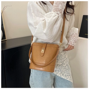 Detailed view of camel bucket bag with golden twist lock and thin shoulder strap