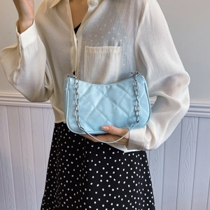 Light blue quilted shoulder bag with silver chain strap shown on a model outfit