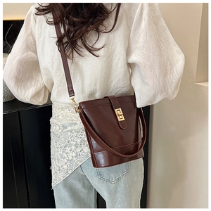 Lifestyle shot of model wearing a vintage dark brown leather bucket bag with gold buckle