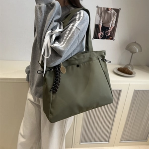 Olive green nylon tote bag with drawstring detail and racket charm on shoulder of a model