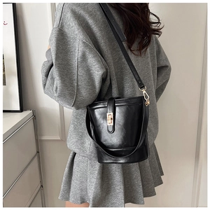 Detail of black bucket tote bag with gold swivel lock and versatile carrying straps