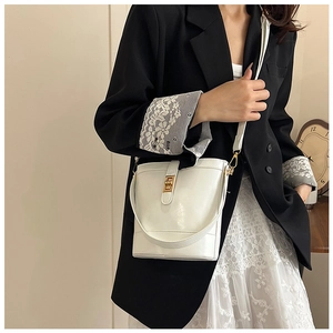 Detail of white leather bucket bag showing gold twist-lock and versatile shoulder strap