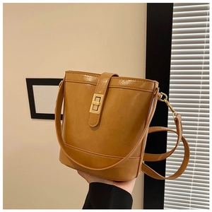 Detail view of mustard yellow vintage bucket bag featuring a gold rectangular twist lock